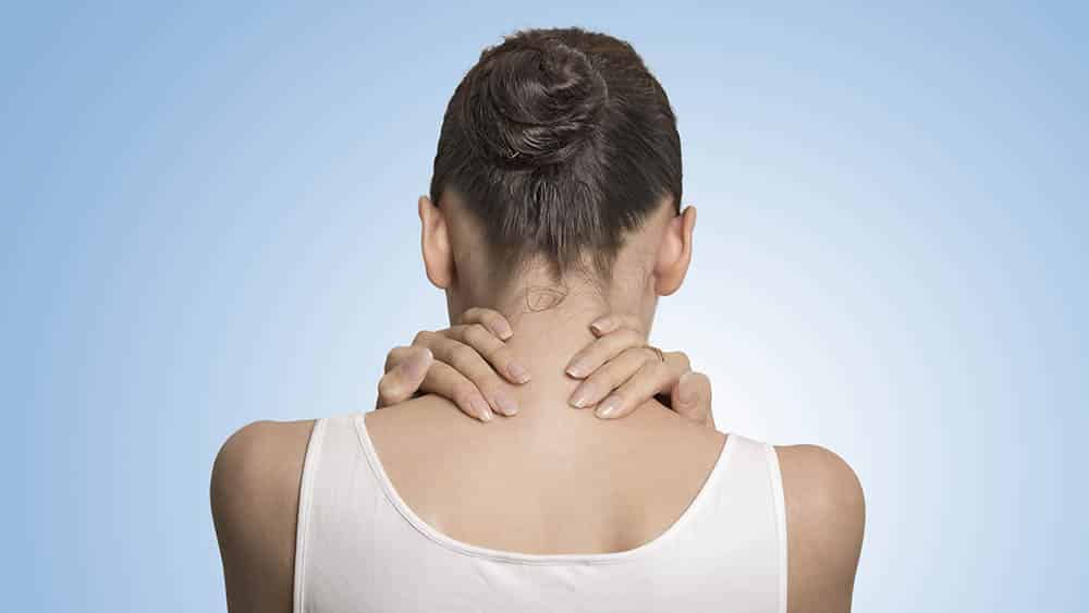 Mulher de costas massageando a nuca aliviando a dor.