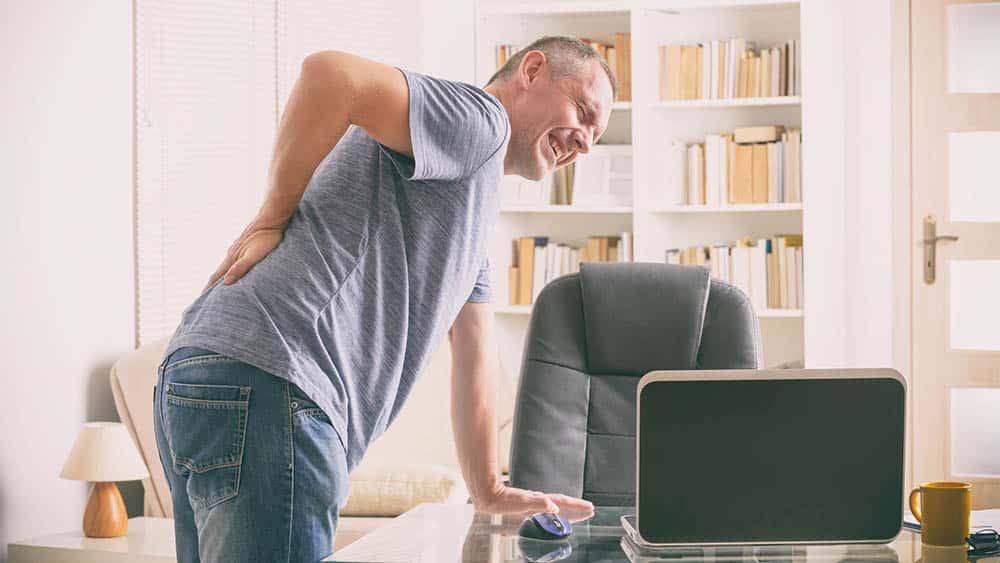 Homem curvado com dor na lombar, um dos sintomas da espondilite anquilosante.