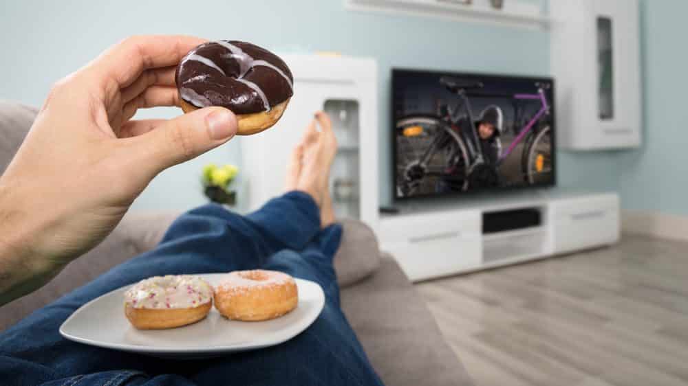 pessoa deitada, comendo donut. veja os mediadores químicos envolvidos na obesidade