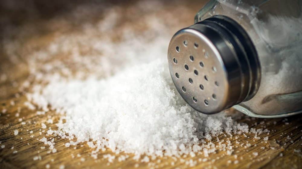saleiro com monte de sal ao lado. quantidade de sal na dieta deve ser moderada
