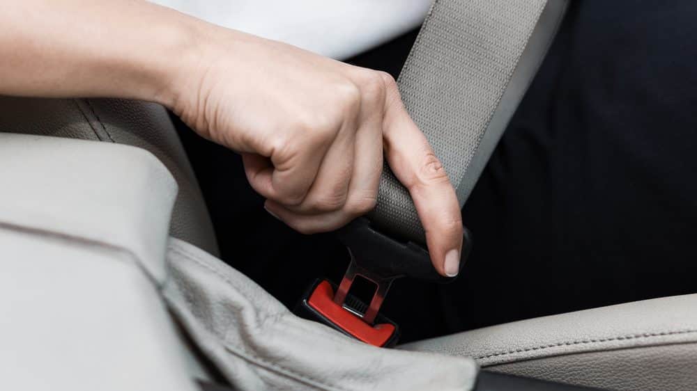 close em mão de mulher colocando o cinto de segurança