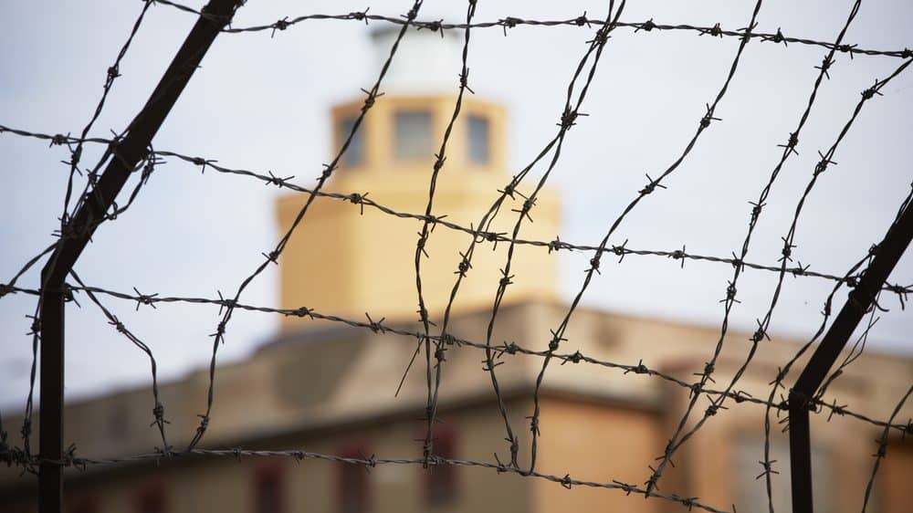 torre de penitenciária cercada por arame farpado. veja as raízes sociais da violência