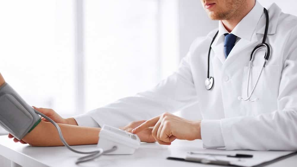Médico medindo a pressão arterial de paciente.