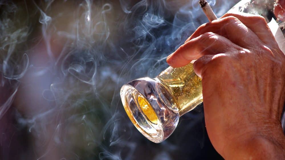 homem bebe e fuma em bar. Proibição de fumo em lugares fechados é essencial