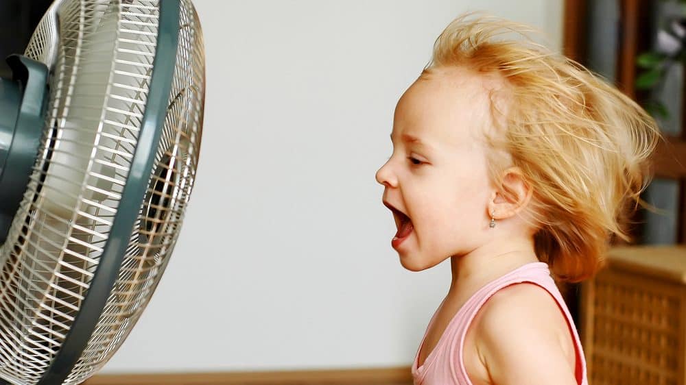 menina em frente ao ventilador. não há relação entre vento e gripe