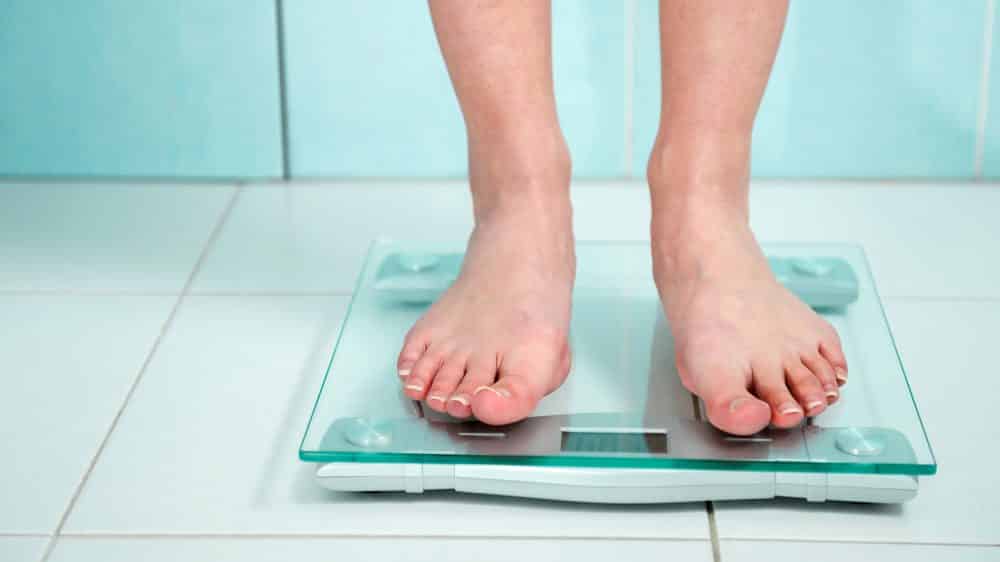 A disseminação da obesidade | Artigo close de pés de mulher se pesando na balança