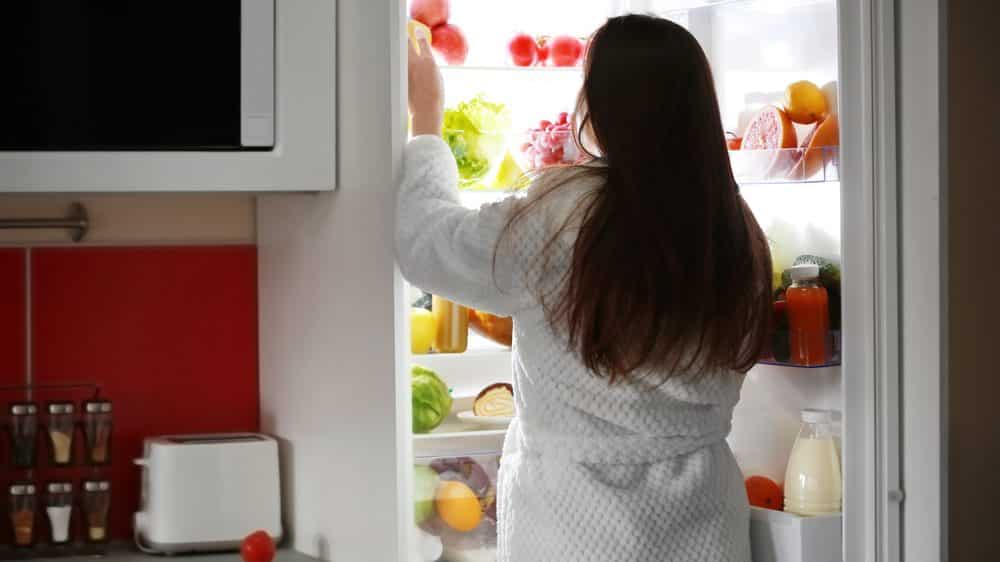 mulher abrindo a geladeira à noite à noite