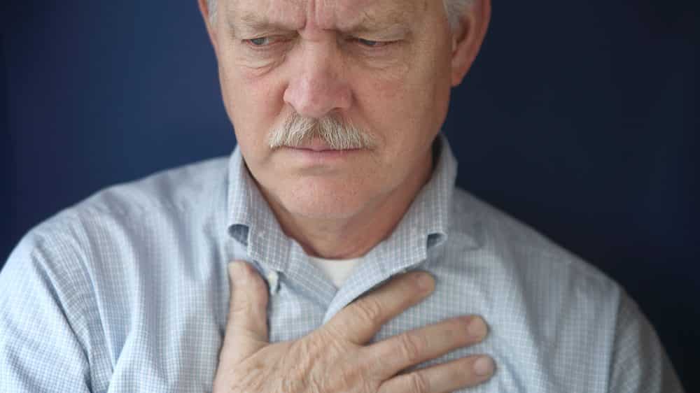 homem com mão no peito em sinal de angina