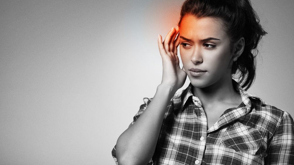 close de mulher com mão na têmpora em sinal de enxaqueca