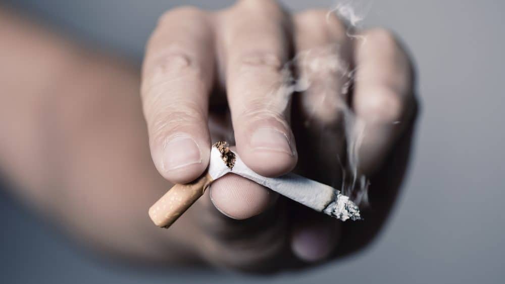 close de mão de fumante quebrando cigarro, como um viciado arrependido