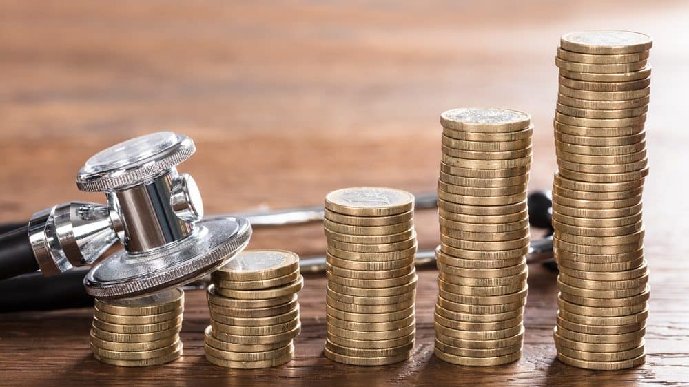 O custo da vida | Artigo estetoscópio ao lado de moedas empilhadas. Evolução do tratamento de câncer encareceu a medicina