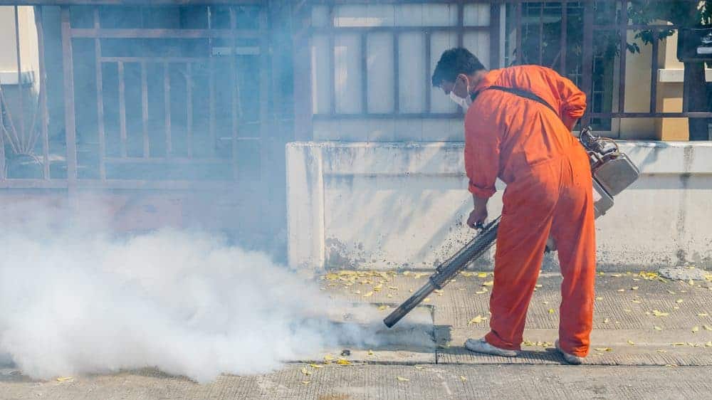 homem faz nebulização em rua para evitar a epidemia de dengue