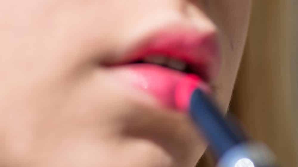 close em rosto de travesti passando batom