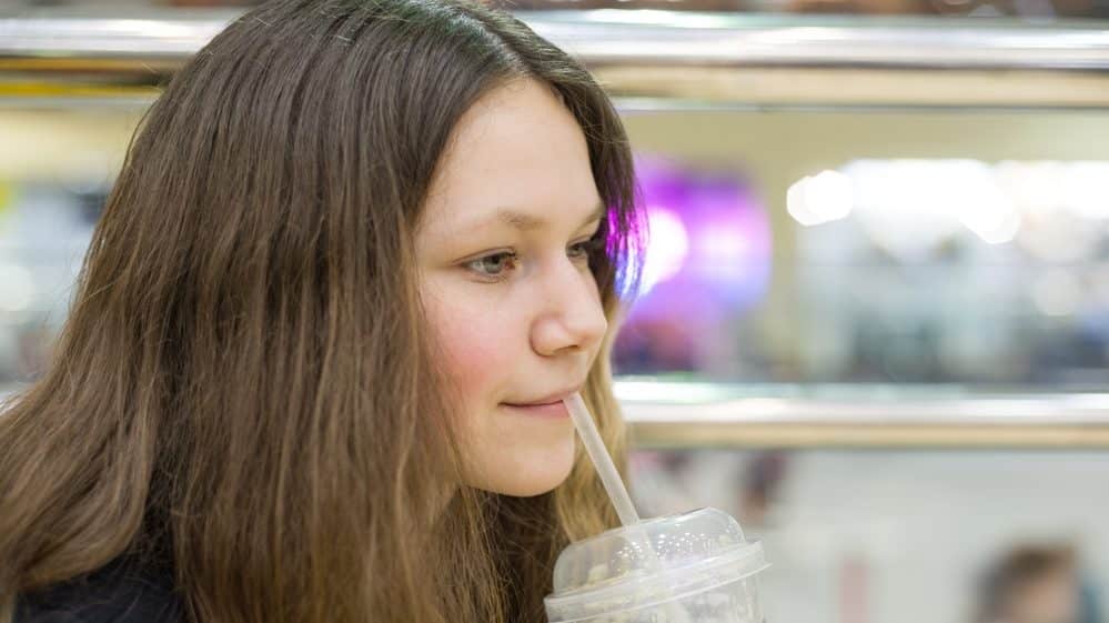 menina jovem toma suco. obesidade na adolescência traz riscos na vida adulta