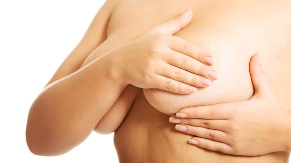mulher examina a mama. obesidade e câncer de mama têm relação
