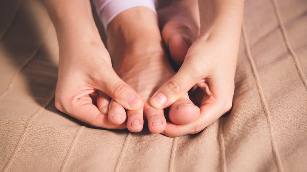 close em pé sendo massageado. gota causa dores fortes na região