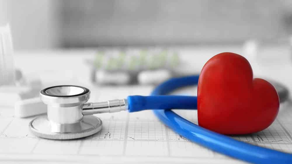 Estetoscópio, pílulas e coração vermelho com um eletrocardiograma