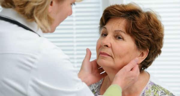 médica examinando pescoço de paciente mulher