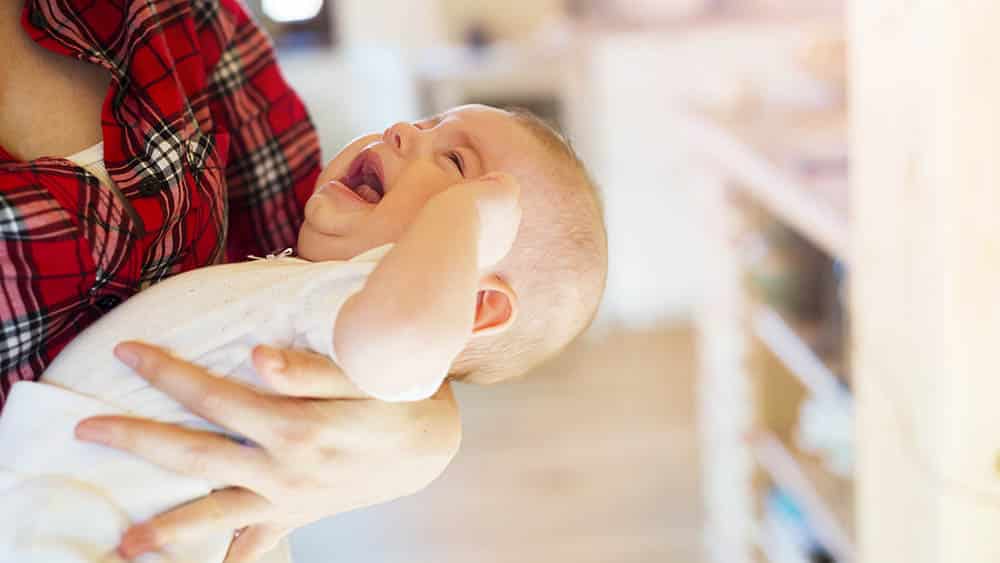bebê chorando nos braços da mãe.
