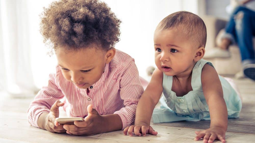 meninas pequenas brincam no chão com celular. Problemas de fala dificultam reconhecimento de vozes
