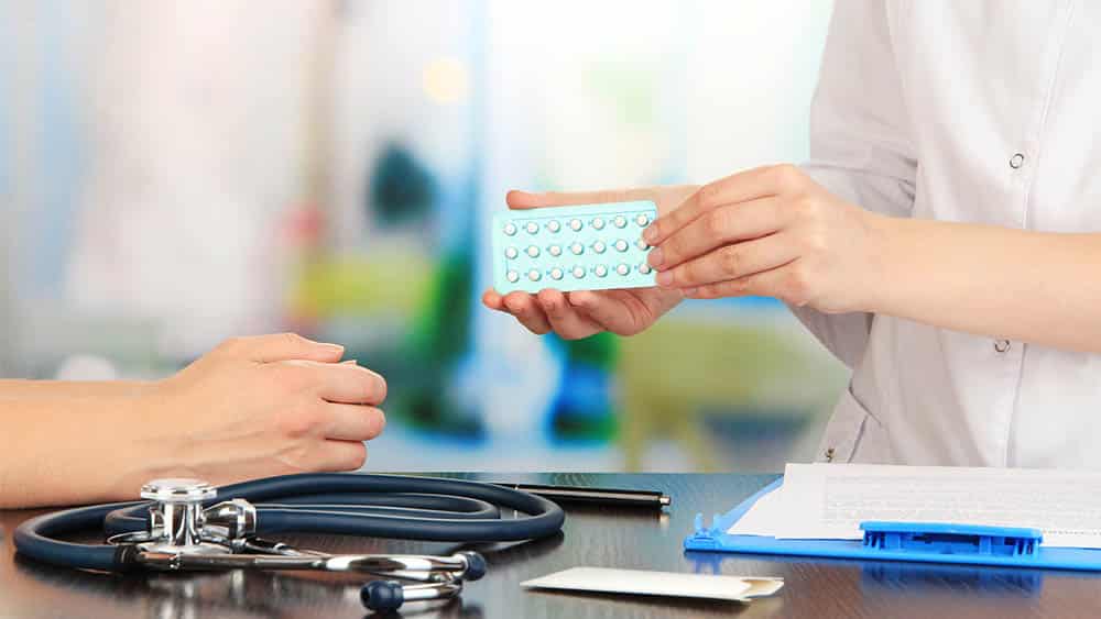 Ginecologista entregando cartela de anticoncepcionais para paciente,