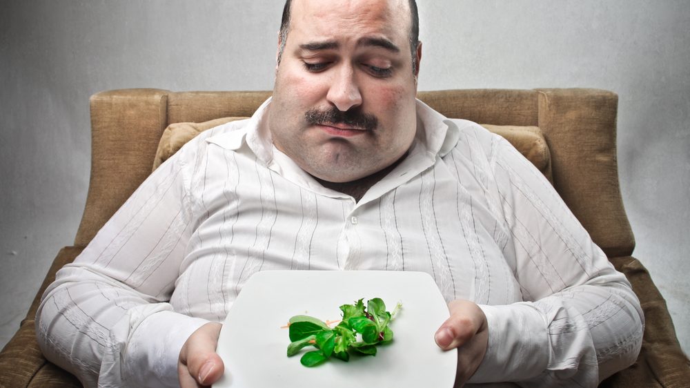 homem obeso diante de prato de salada. Dieta restritiva é comum em spa