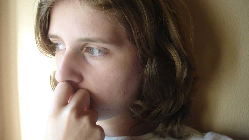 Close em rosto de mulher jovem com olhar distante.