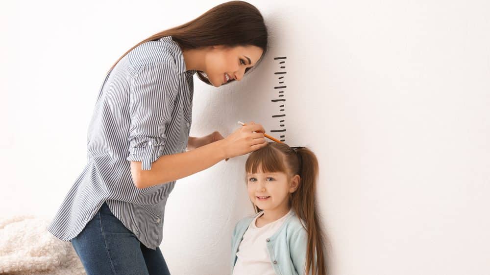 Baixa estatura | Artigo mãe mede filha encostada na parede. baixa estatura pode ter causas genéticas