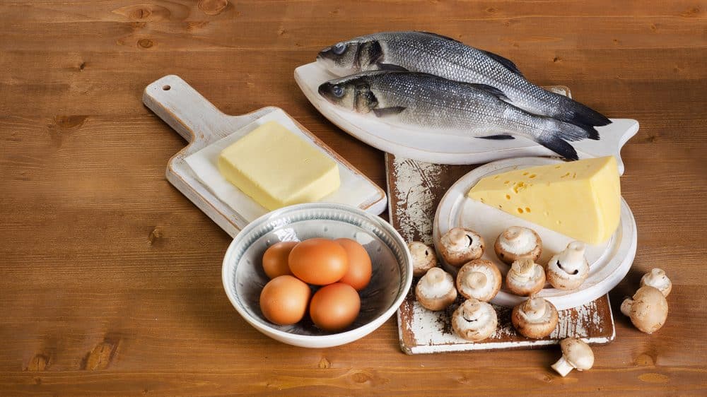 alimentos com vitamina D em mesa de madeira. ovos, peixe cru, manteiga e alho