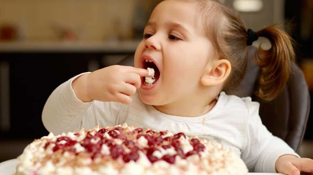 menina comendo bolo. mecanismos envolvidos no comer compulsivo são semelhantes aos do vício