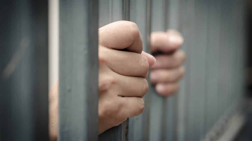 mãos de homem atrás das grades. estupradores devem ser afastados do convívio social