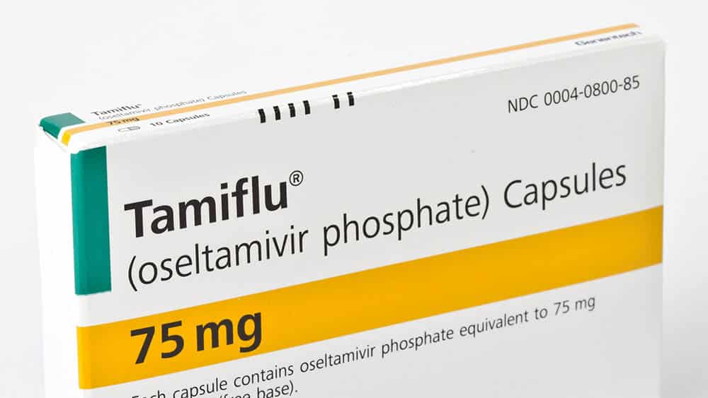 Detalhe de uma caixa do medicamento Tamiflu sobre um fundo branco.