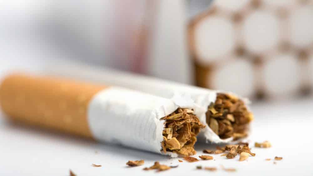 close de cigarro quebrado ao meio sobre a mesa. nicotina é considerada porta de entrada para outras dorgas