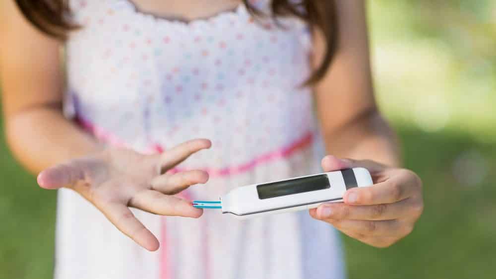 criança com diabetes tipo 1 checa glicemia no dedo