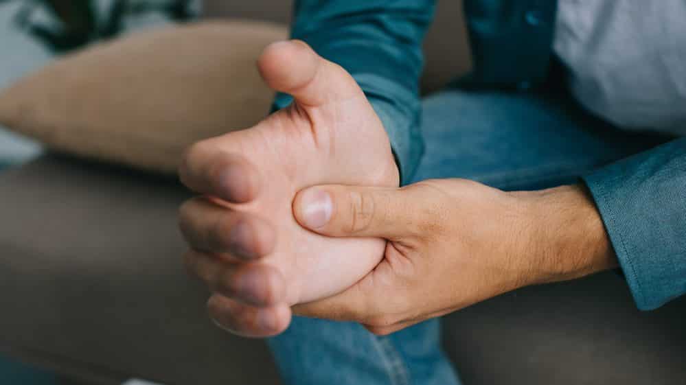 close de punho de homem com dor articular causada pela febre chikungunya