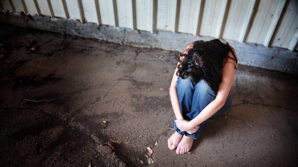 mulher com a cabeça entre os joelhos. violência universitária deve ser enfrentada