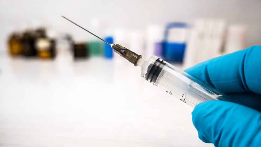 mão de médico segura seringa. vacina para a dengue está sendo testada