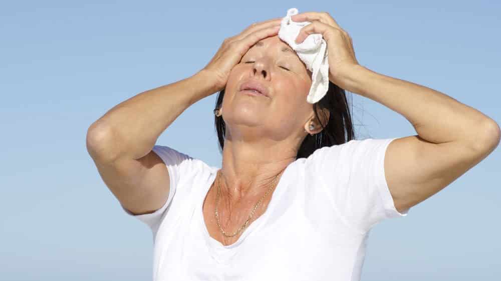 mulher com calor enxuga a testa. inicio da menopausa é marcado por ondas de calor