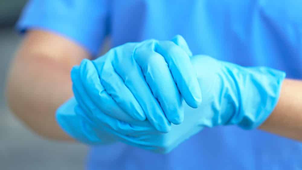 mãos de medico com luvas. denunciar para a polícia pacientes que fazem aborto é medicina policialesca