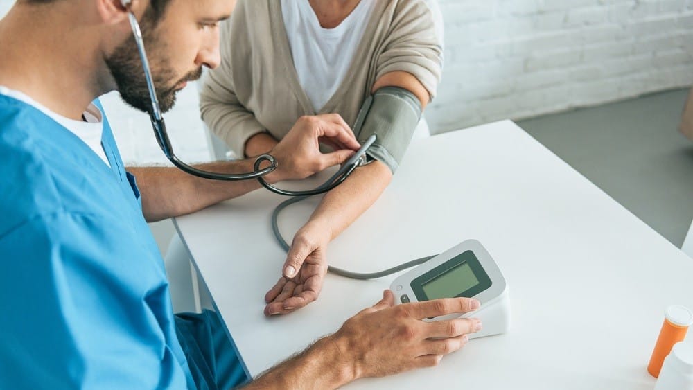 Enfermeiro aferindo a pressão arterial de uma paciente.