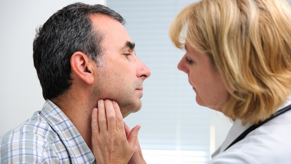 Médica examinando a garganta de paciente.