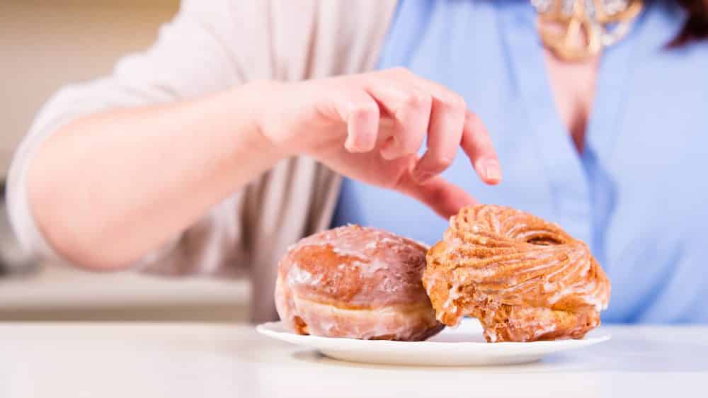 Reclama pro bispo | Artigo mão estendida para alcançar prato de rosquinhas. obesidade mundial tem crescido