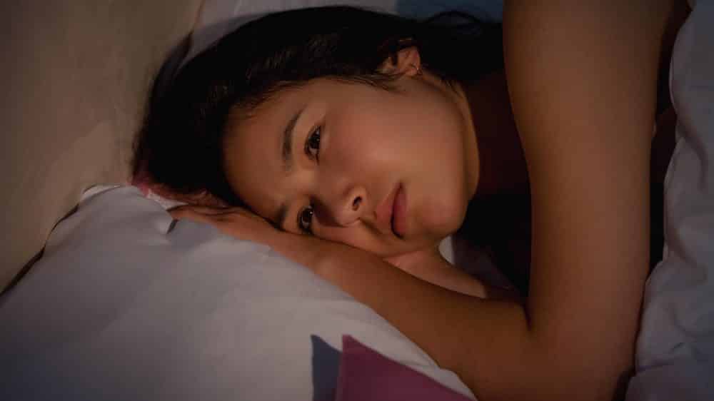 Insônia e mortalidade | Artigo mulher jovem deitada, com insônia. insônia e mortalidade têm relação