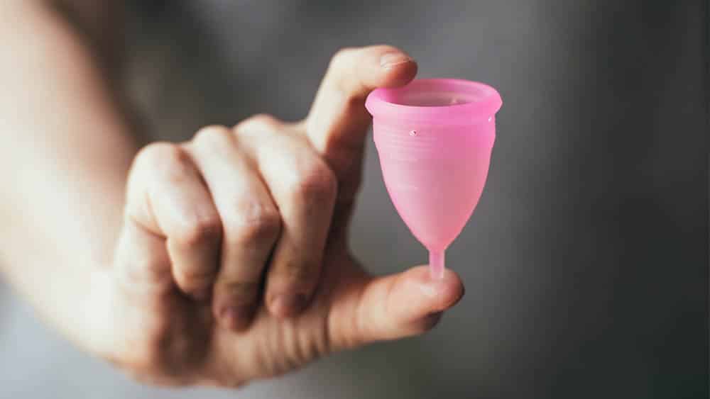 Mão feminina segurando um coletor menstrual