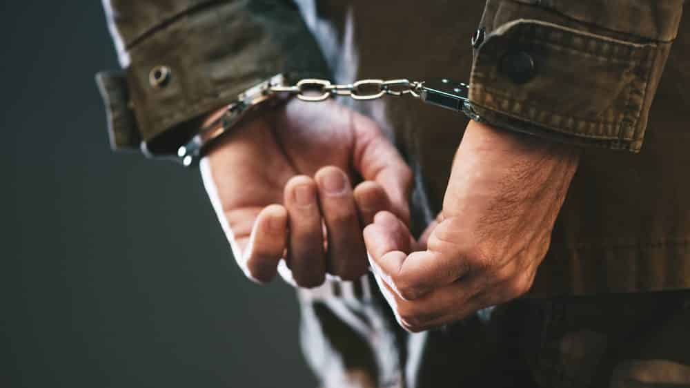 homem com mãos para trás, algemado. é preciso distinguir melhor usuário e traficante de drogas