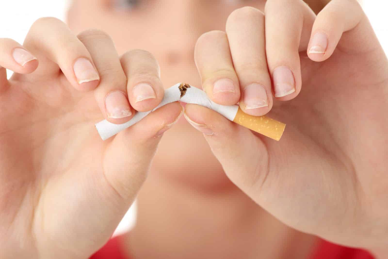 Mãos quebrando um cigarro ao meio.