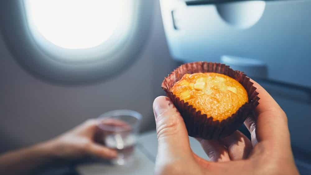 homem segura muffin em avião. excesso de peso é problema grave de saúde