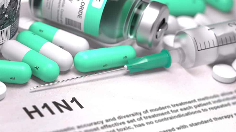 Quem deve tomar a vacina contra a H1N1 H1N1 escrito em uma folha e, em cima, seringa, comprimidos e frasco de vacina.