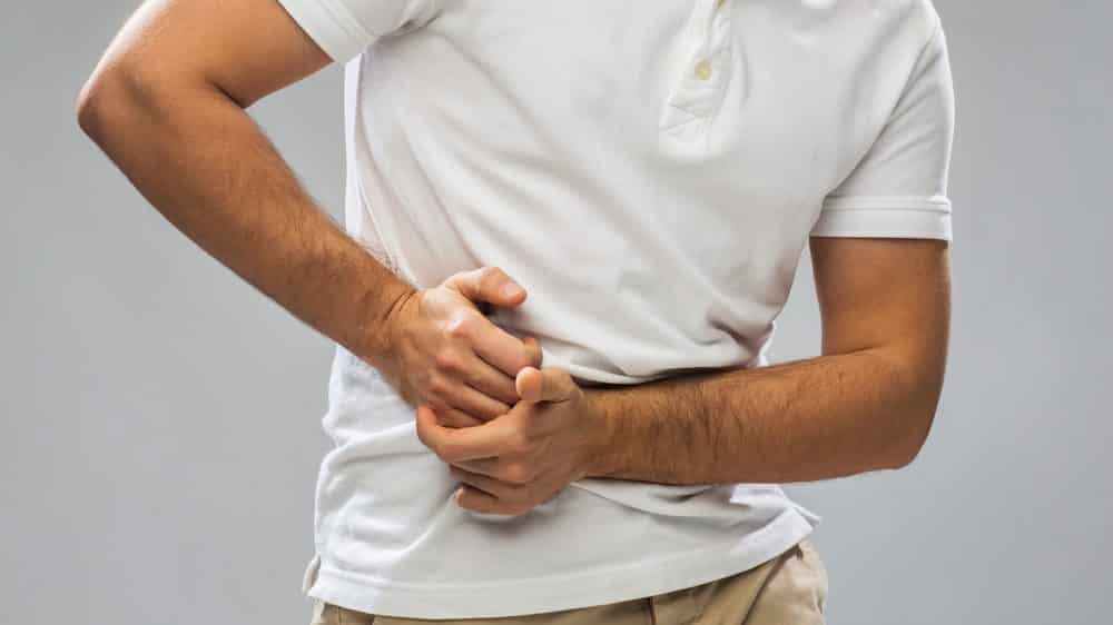 Apendicite | Artigo Homem com mão no lado inferior do abdômen, em sinal de dor. Cirurgia de apendicite ainda é indicada