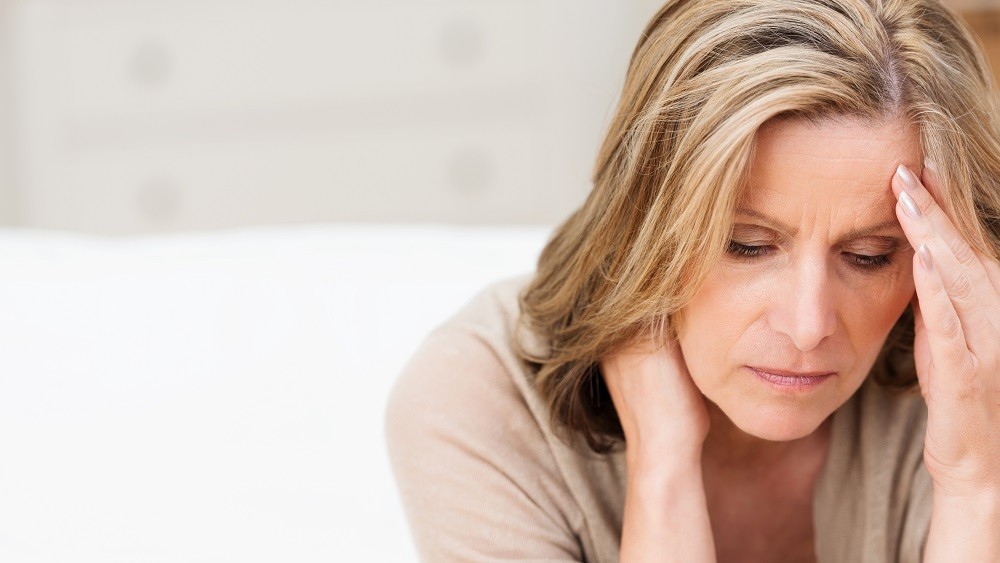 Mulher sentindo desconforto. menarca precoce influi na menopausa precoce